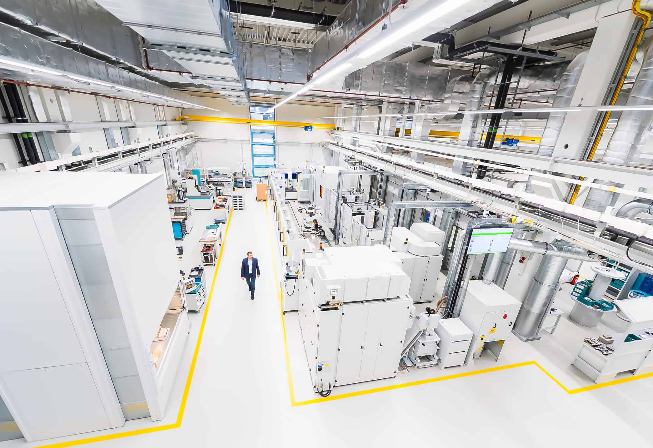 High angle view of manager walking along factory aisle factory automation, improve product lead time, digital production