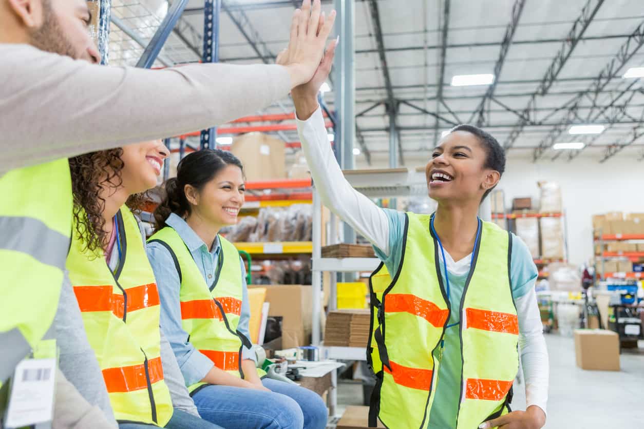 Warehouse employee receives congratulations during team meeting