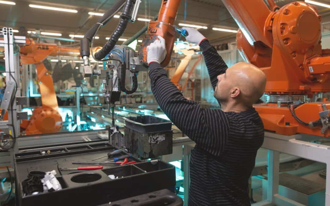 An expert technician in the field of automotive digital quality, wearing protective gear, is engaged in the precise task of fixing a cobalt component within an Industry 4.0 automotive manufacturing environment. The scene is equipped with state-of-the-art digital tools and machinery, emphasizing the role of advanced technologies in enhancing manufacturing precision and efficiency. In the background, computer monitors display vital real-time diagnostics and data analytics, illustrating the critical integration of digital quality control measures in modern vehicle production processes