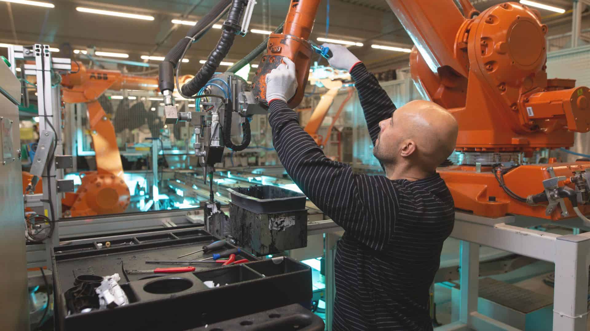 An expert technician in the field of automotive digital quality, wearing protective gear, is engaged in the precise task of fixing a cobalt component within an Industry 4.0 automotive manufacturing environment. The scene is equipped with state-of-the-art digital tools and machinery, emphasizing the role of advanced technologies in enhancing manufacturing precision and efficiency. In the background, computer monitors display vital real-time diagnostics and data analytics, illustrating the critical integration of digital quality control measures in modern vehicle production processes